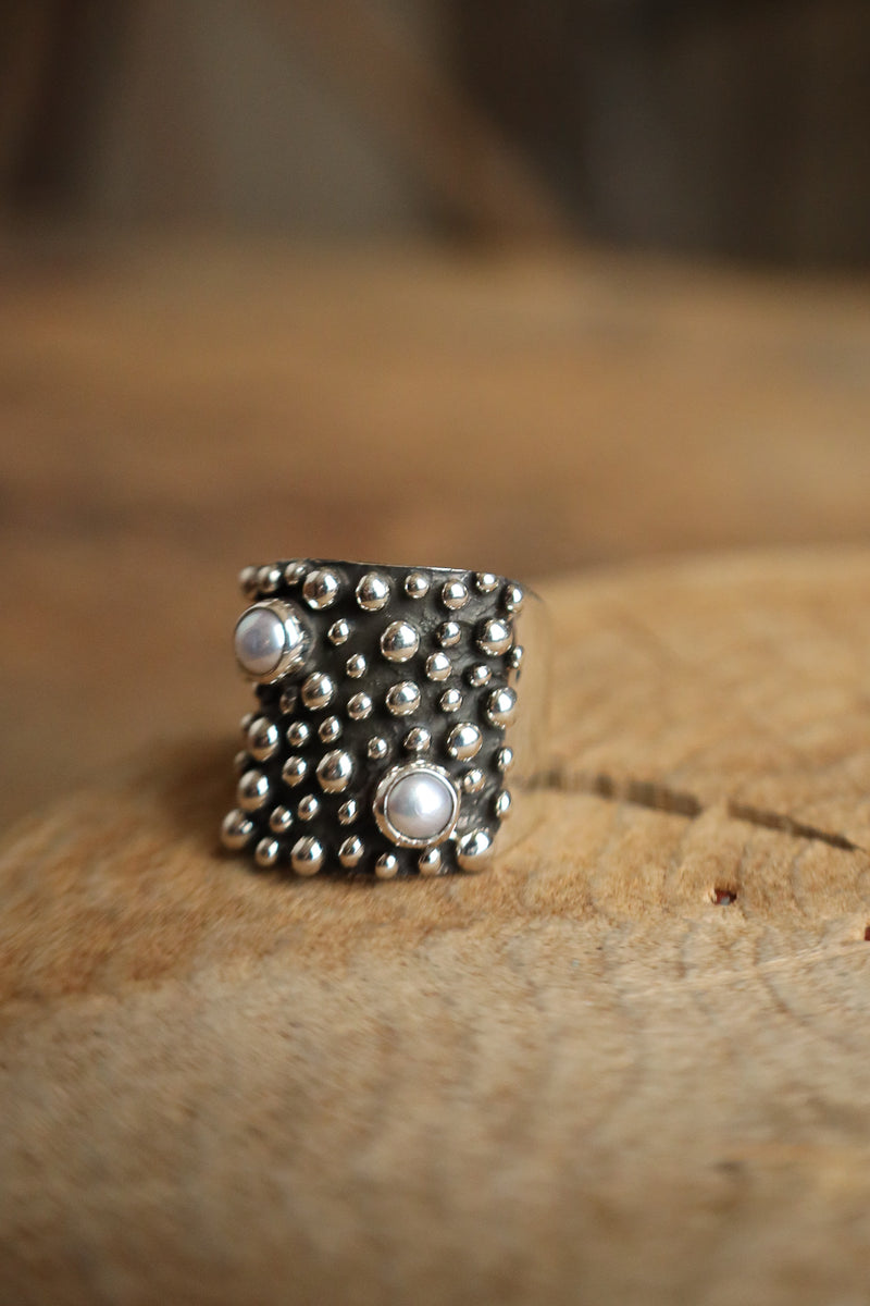 Silver ring with bead detailing on a wooden surface