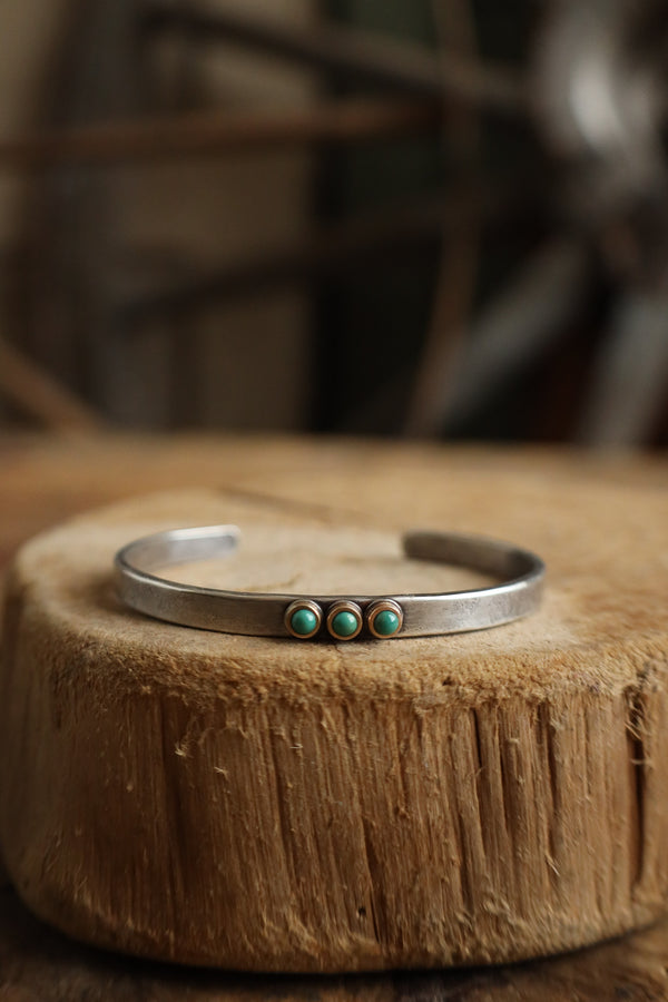 Silver bracelet with turquoise stones on a wooden surface