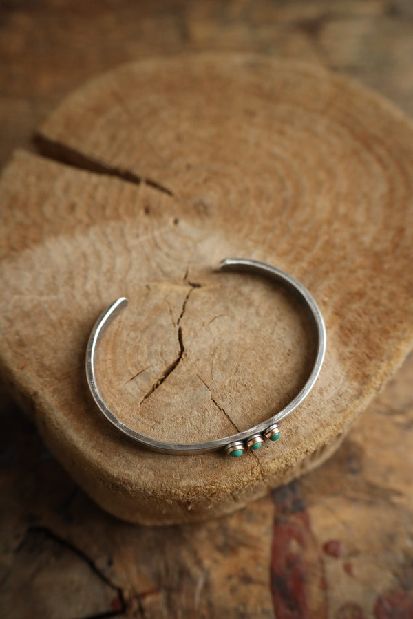 Silver bracelet with green stones on a textured stone surface