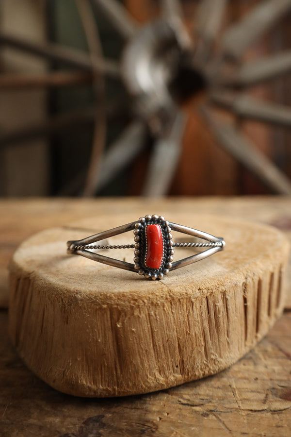 Silver ring with red stone on a wooden block with a rustic background