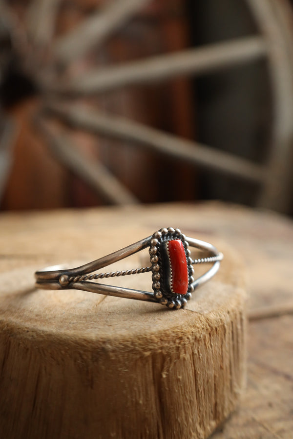 Silver bracelet with a red stone on a wooden surface with a blurred background