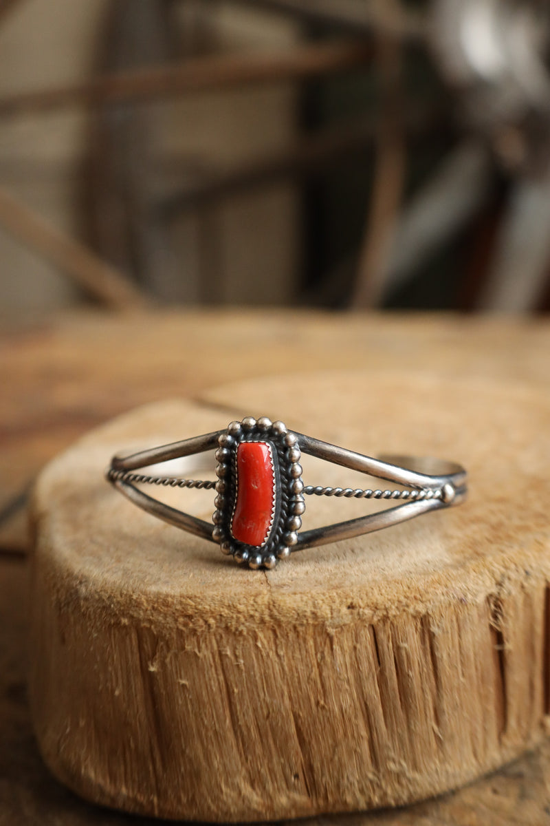 Silver bracelet with a red stone on a wooden surface