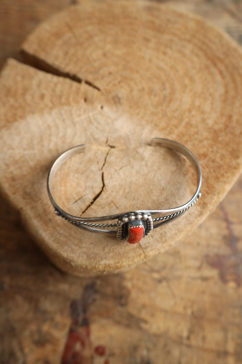 Silver bracelet with a red stone on a wooden surface