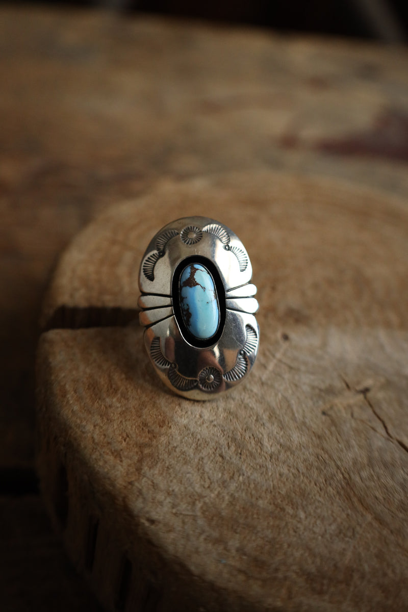 Silver ring with a turquoise stone on a wooden surface