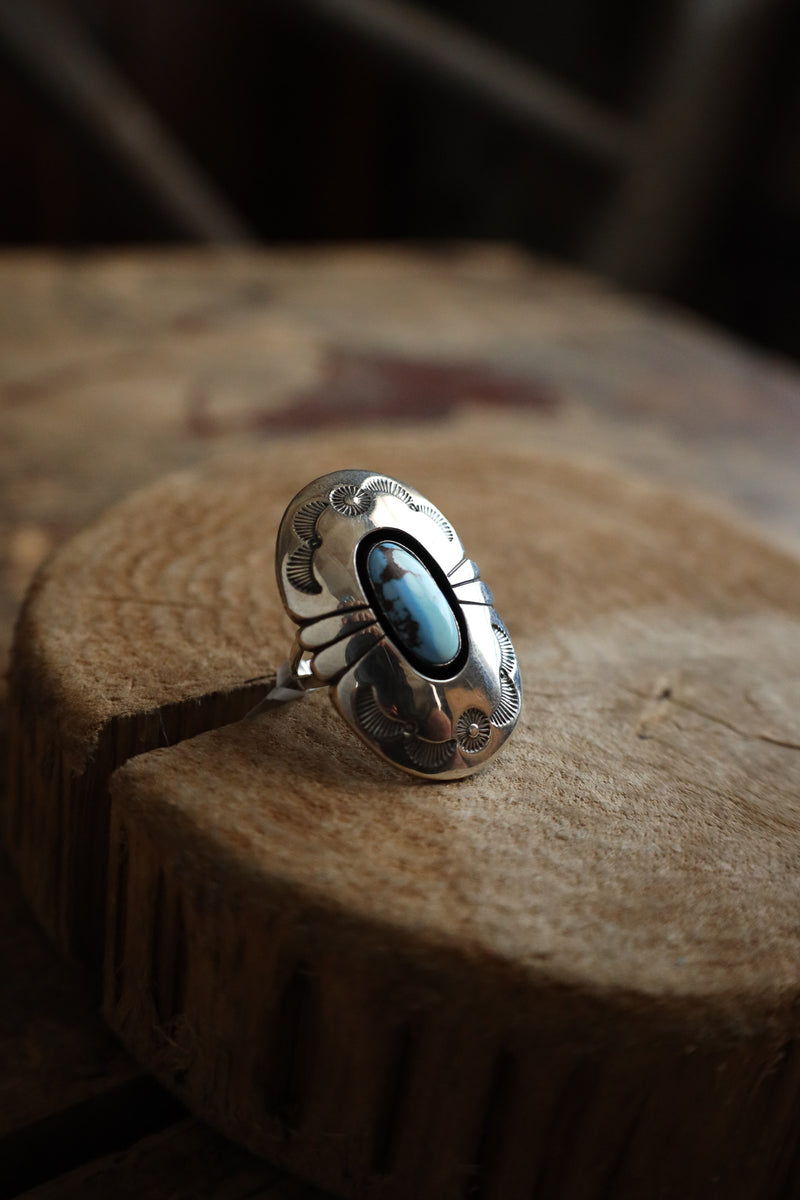 Silver ring with a blue stone on a wooden surface