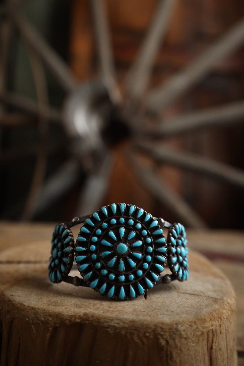 Turquoise bracelet on a wooden block with a blurred wheel in the background