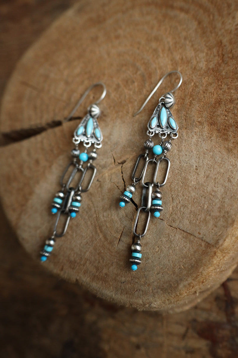 Silver earrings with turquoise beads on a wooden surface