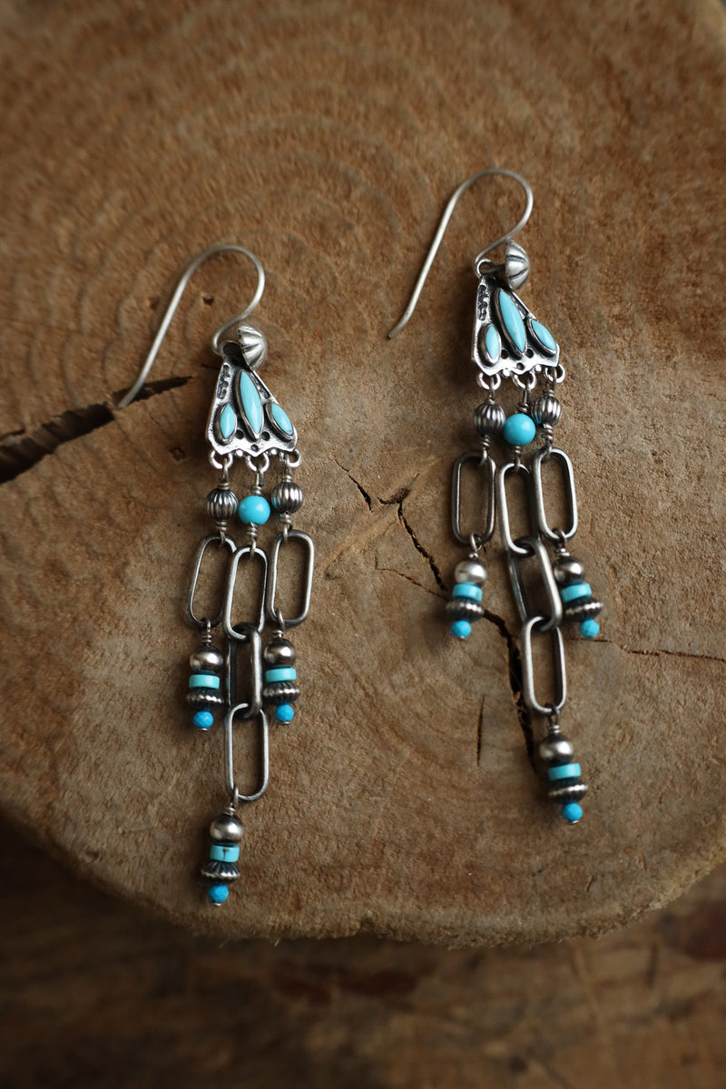 Pair of silver and turquoise earrings on a wooden surface