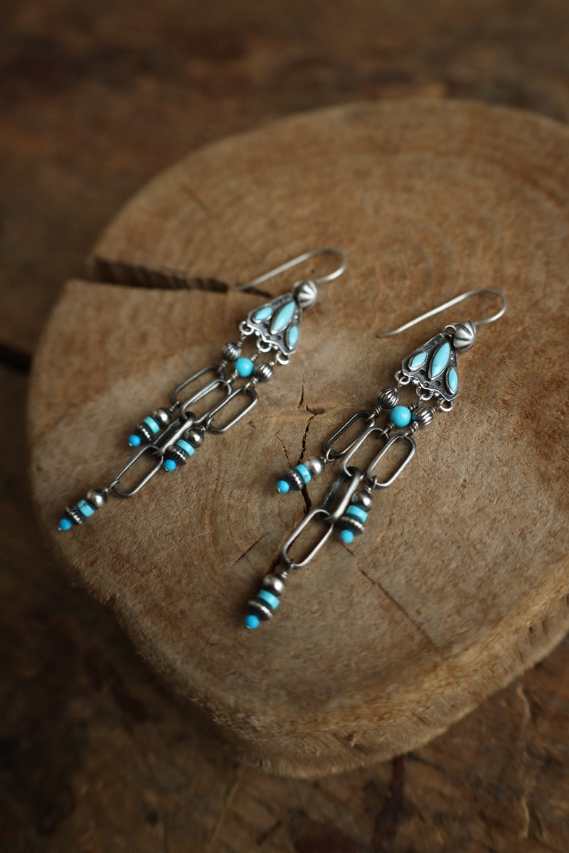 Silver earrings with turquoise beads on a wooden surface