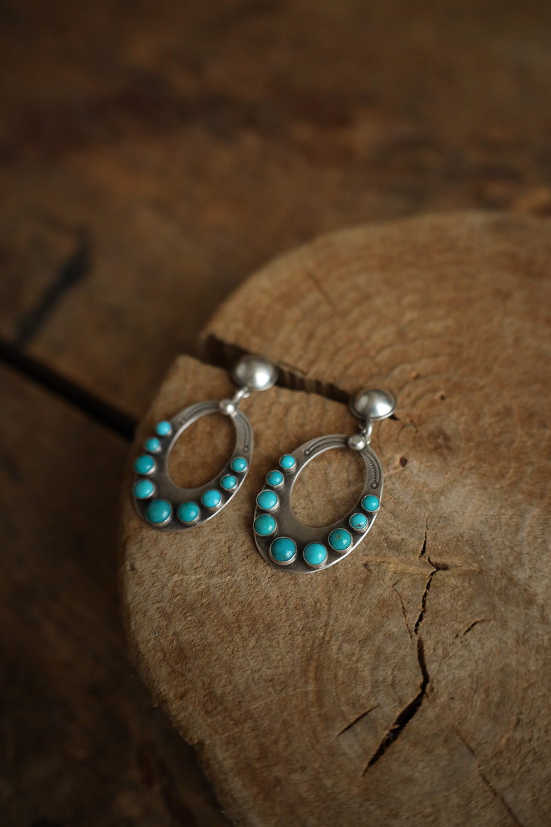 Silver earrings with turquoise stones on a wooden surface
