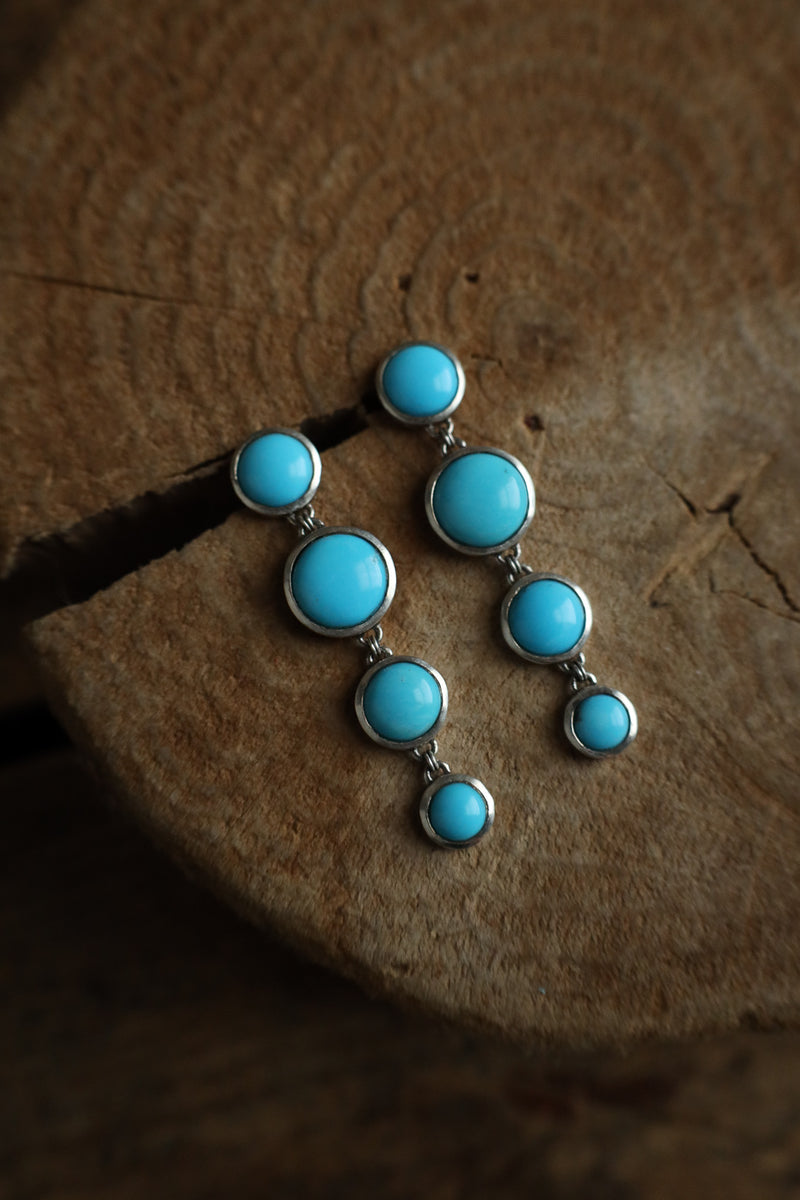 Turquoise stone earring on a wooden surface