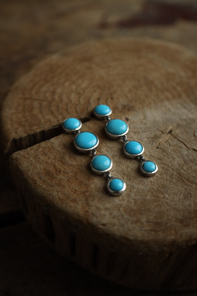 Turquoise stone and silver pendant on a wooden surface