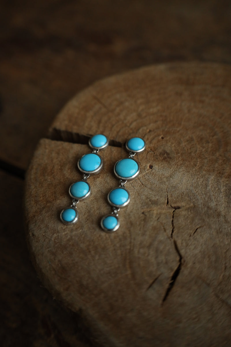 Turquoise stone earrings on a wooden surface