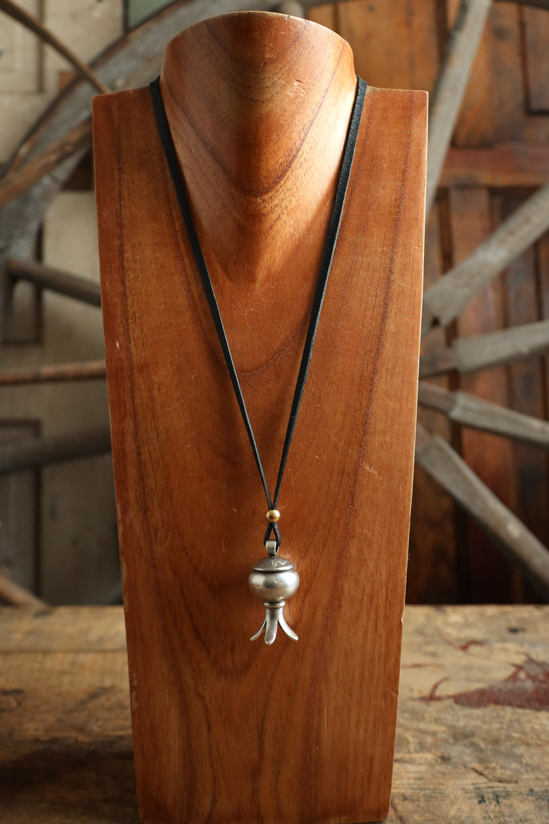 Wooden necklace stand with a pendant necklace against a rustic background