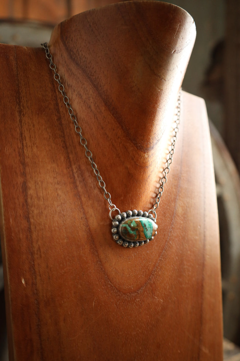 Necklace with a turquoise pendant on a wooden mannequin