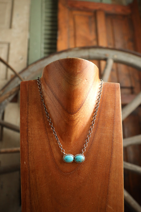 Necklace with turquoise stones on a wooden mannequin against a rustic background