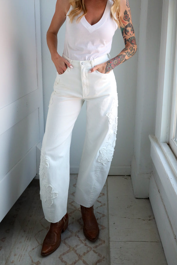 Person wearing a white outfit with brown boots in a minimal indoor setting