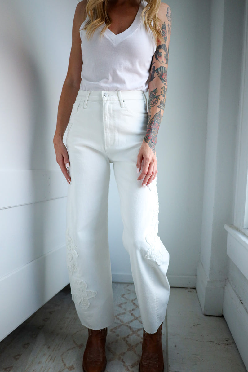Person wearing a white tank top and pants in a minimal indoor setting