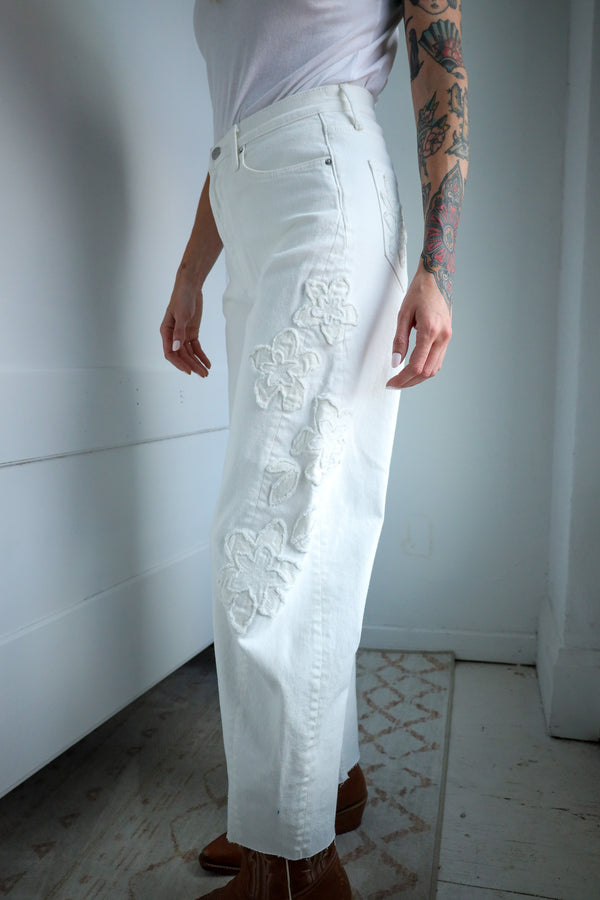 Person wearing white lace pants with a plain background
