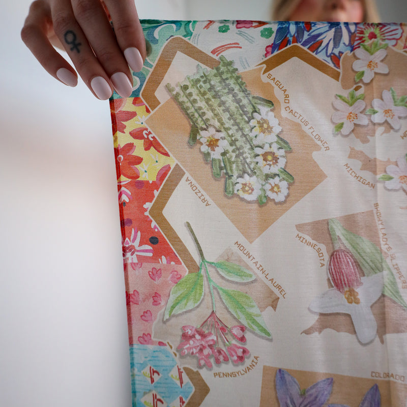 Person holding a colorful map with floral and nature-themed illustrations on a white background
