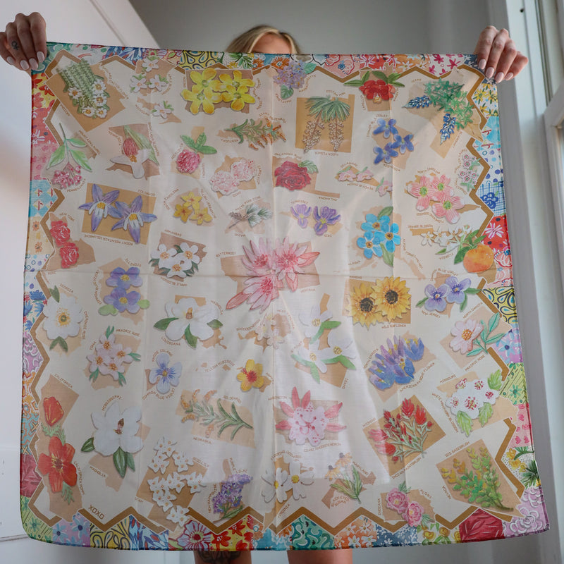 Person holding a large floral-patterned fabric with colorful flowers and geometric shapes.