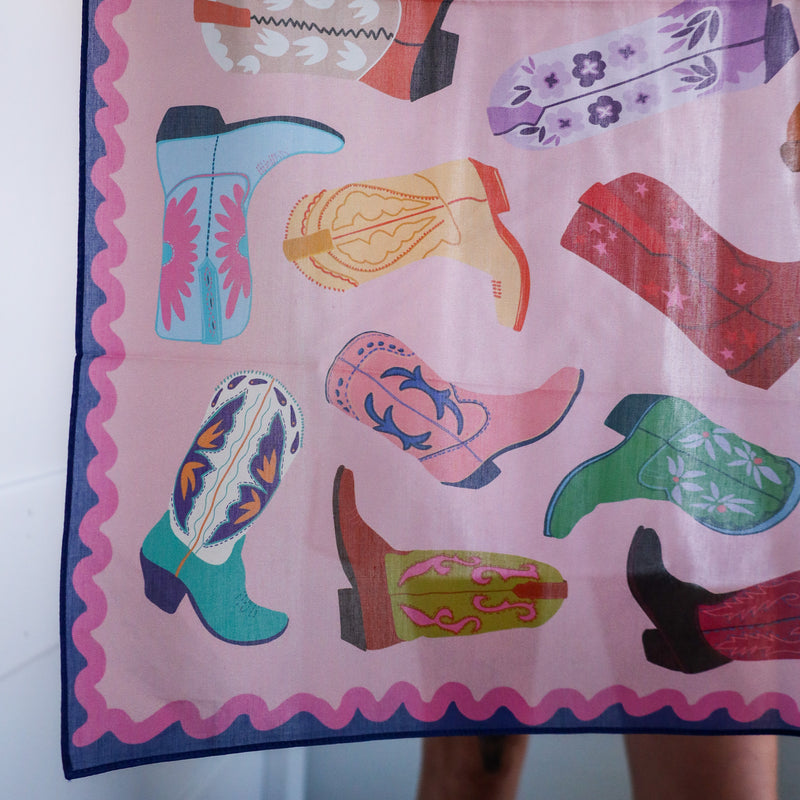Colorful scarf with cowboy boot pattern on a pink background