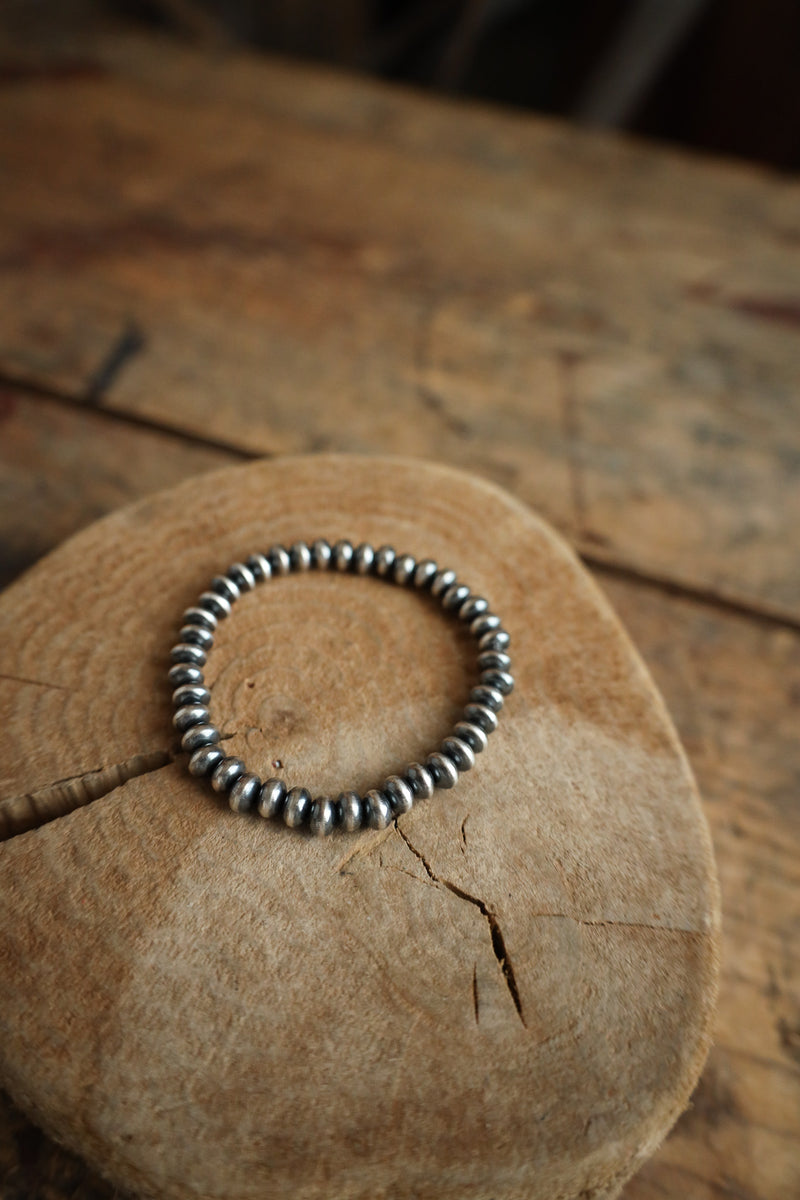 Silver beaded bracelet on a wooden surface