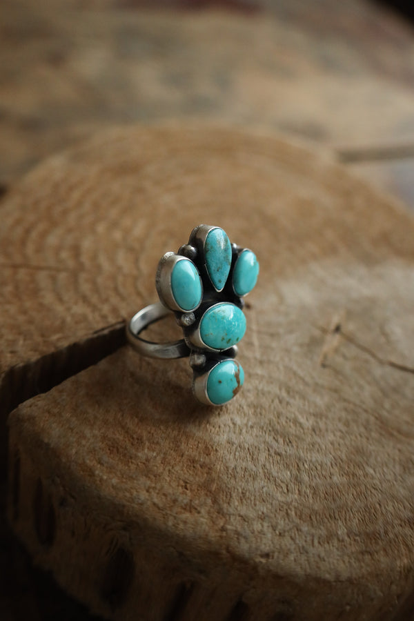 Turquoise ring with paw design on a wooden surface