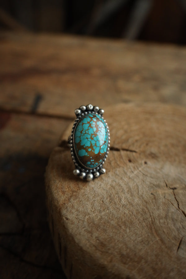 Turquoise ring with silver band on a wooden surface