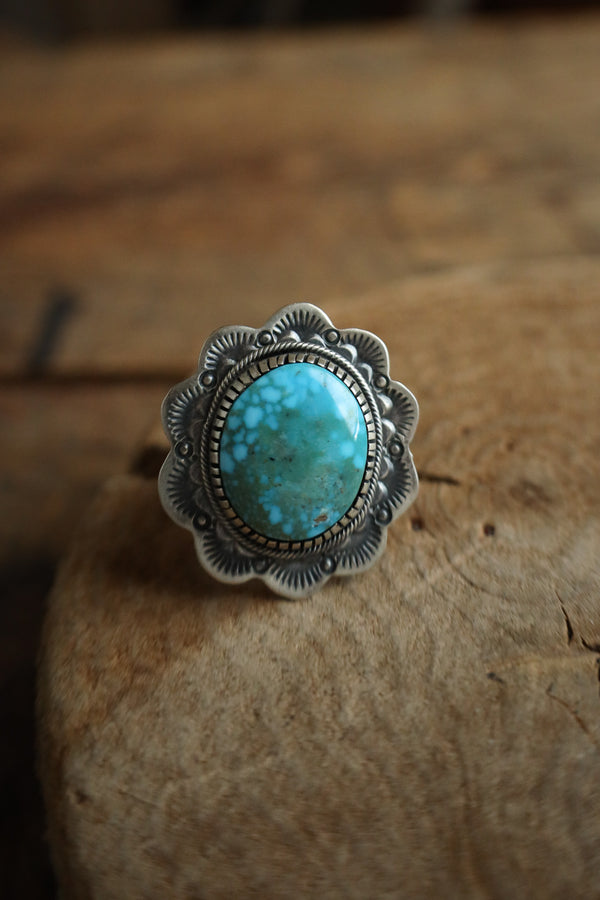 Turquoise ring with silver setting on a wooden surface