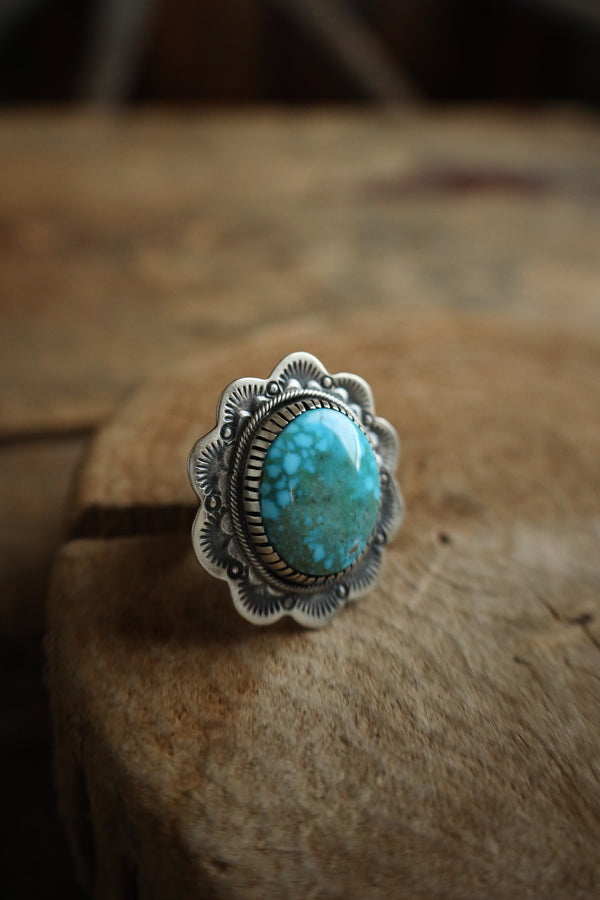 Silver ring with a turquoise stone on a wooden surface