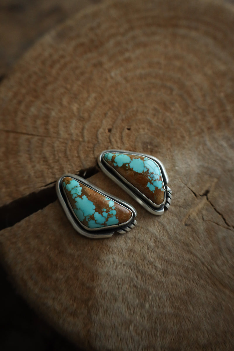 Turquoise and silver earring on a wooden surface