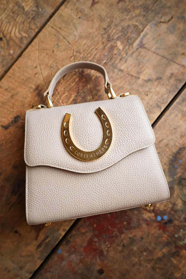 Beige handbag with gold accents on a wooden surface