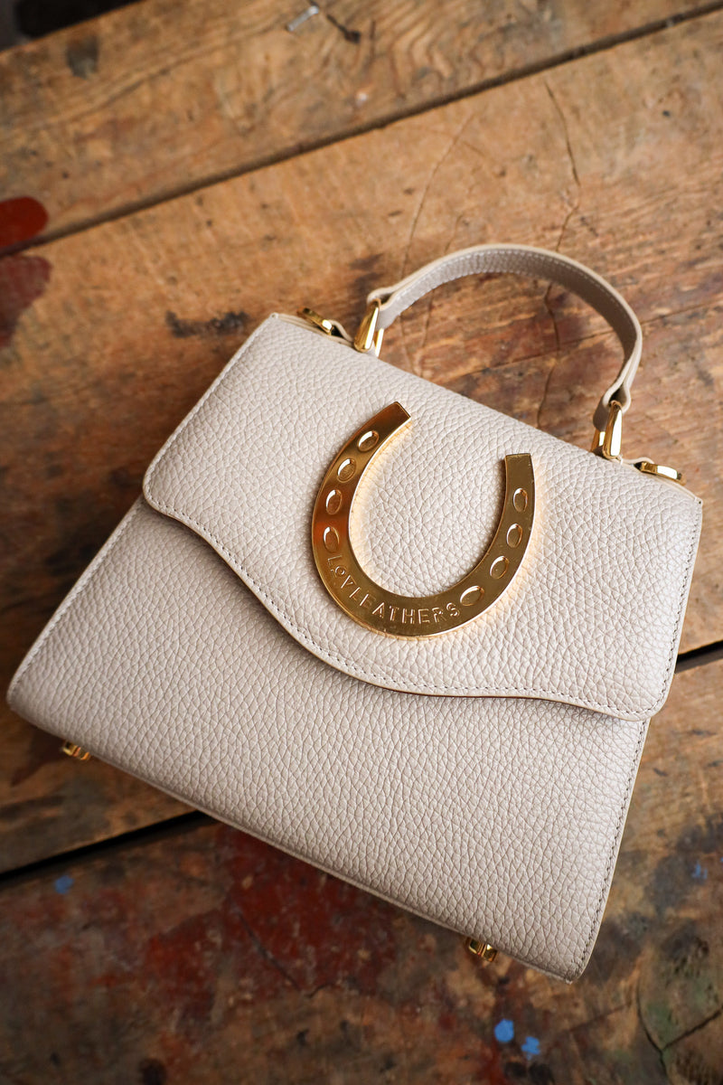 Beige handbag with gold clasp on a wooden surface