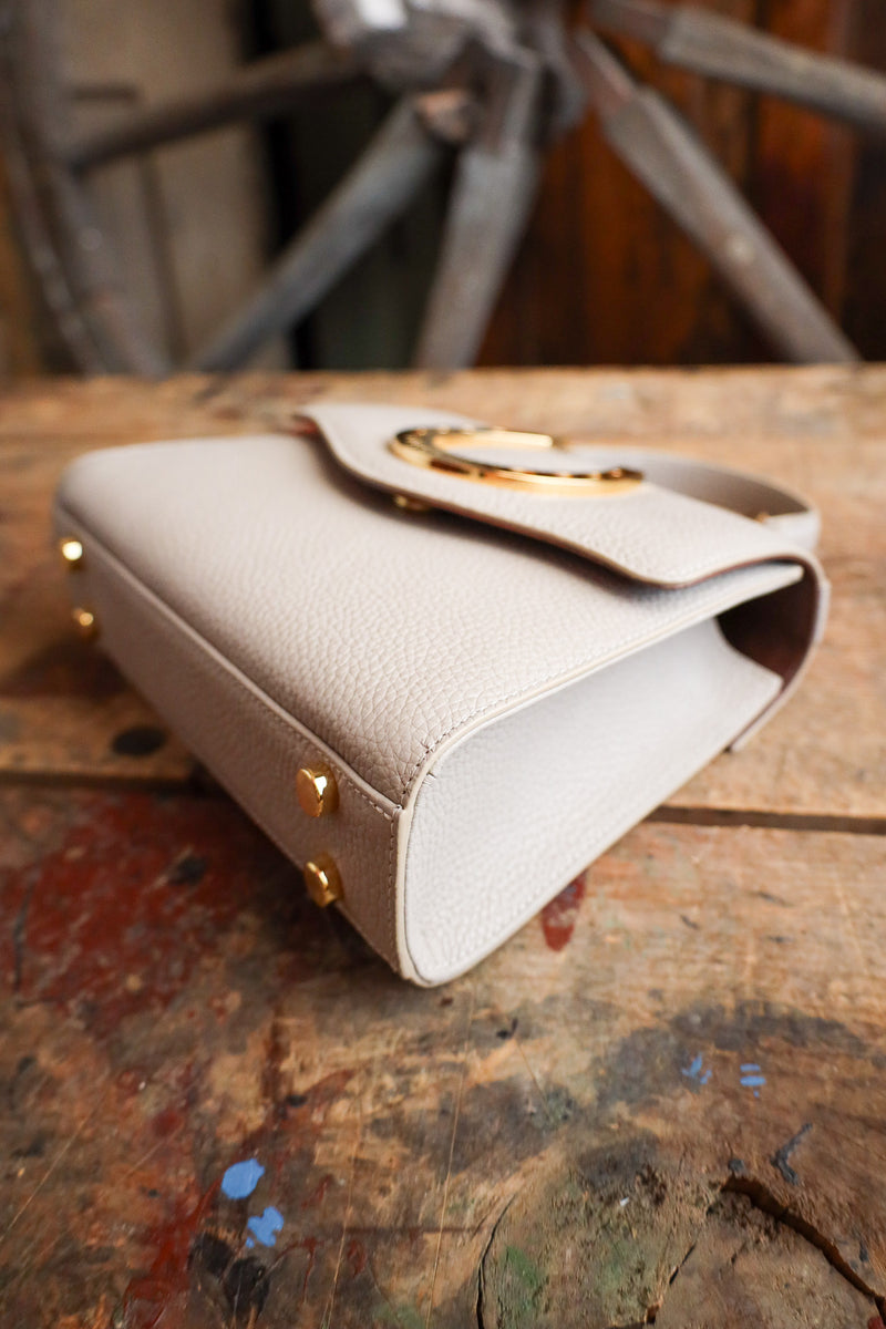 Beige handbag with gold accents on a rustic wooden surface