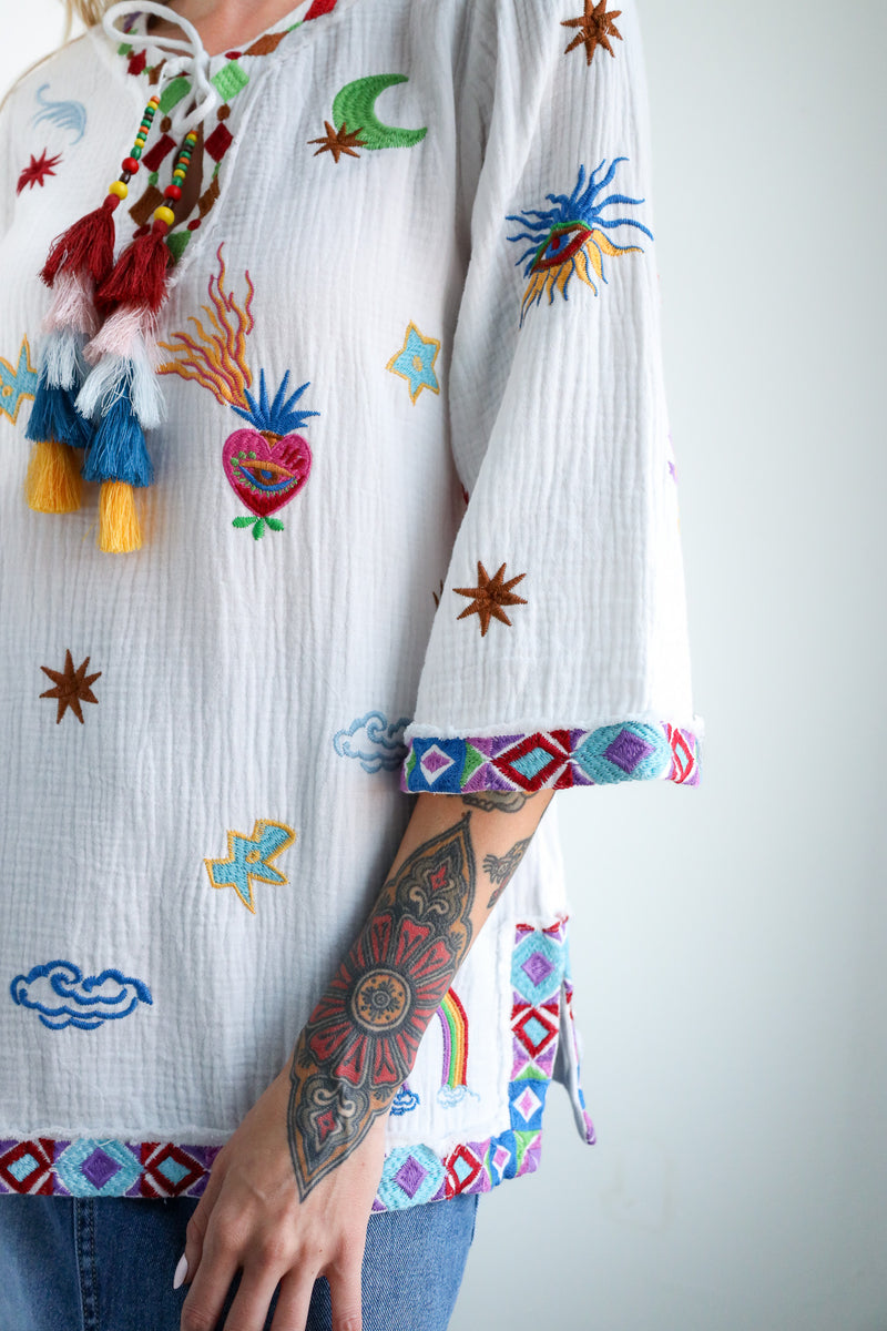 Colorful embroidered blouse with intricate patterns on a plain background