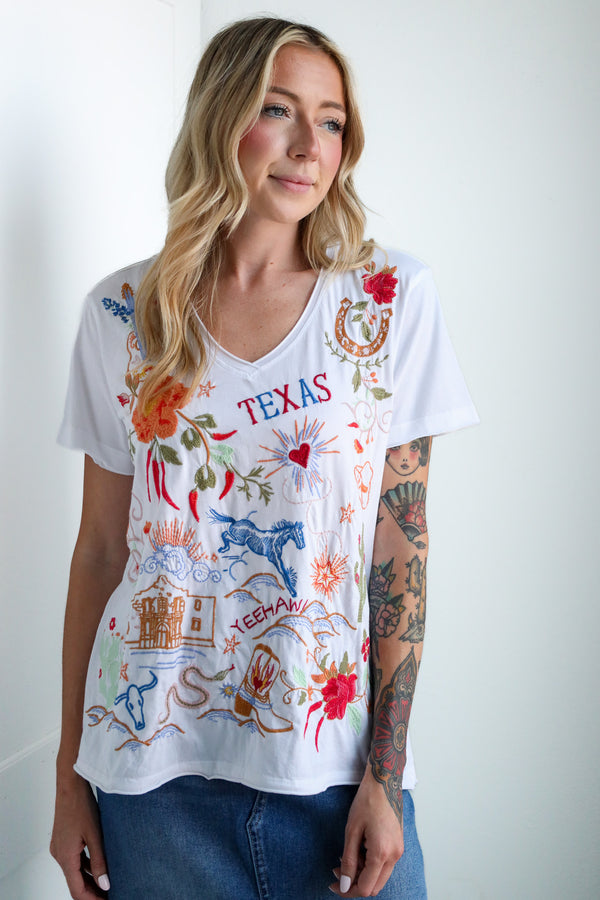 Woman wearing a white t-shirt with colorful graphics and 'Texas' text on a plain background