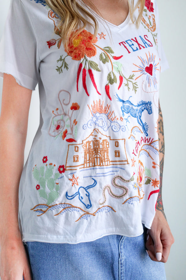 White t-shirt with colorful Texas-themed graphics worn by a person.