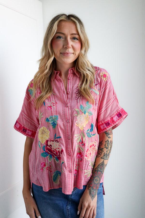 Woman wearing a pink floral blouse against a white background