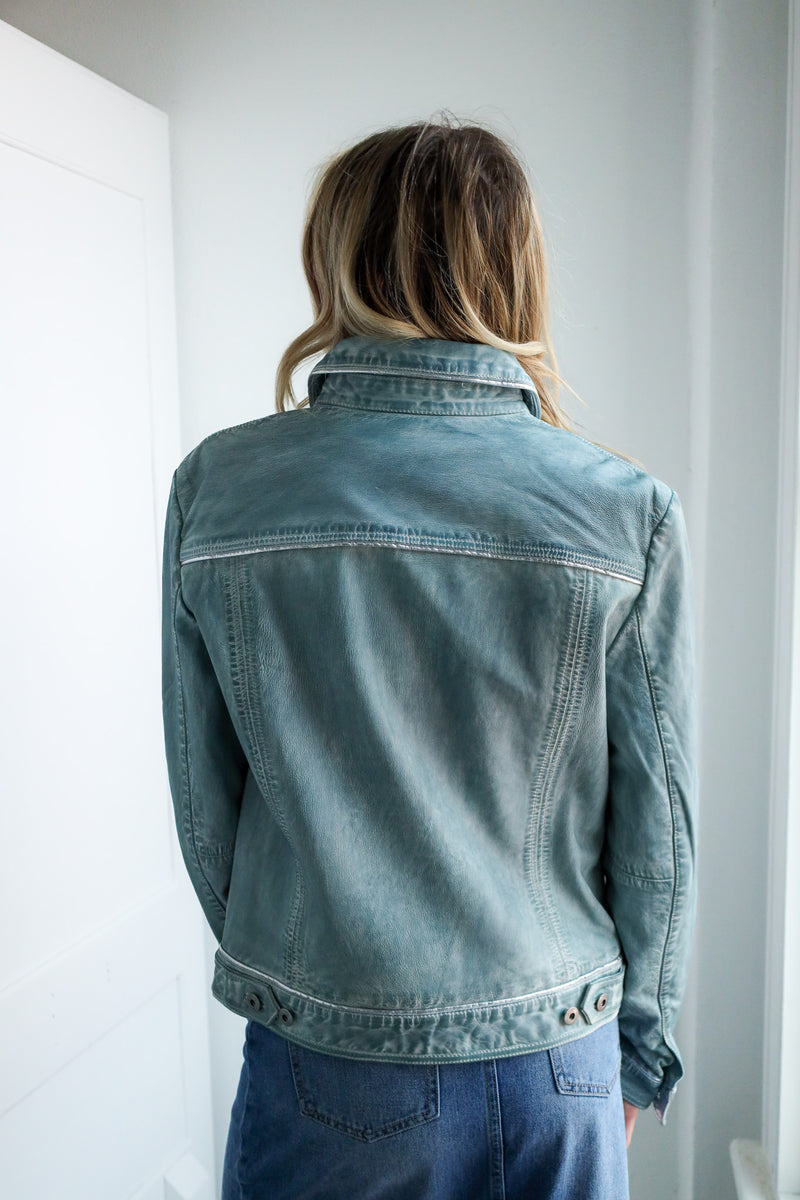 Person wearing a denim jacket in a minimal indoor setting