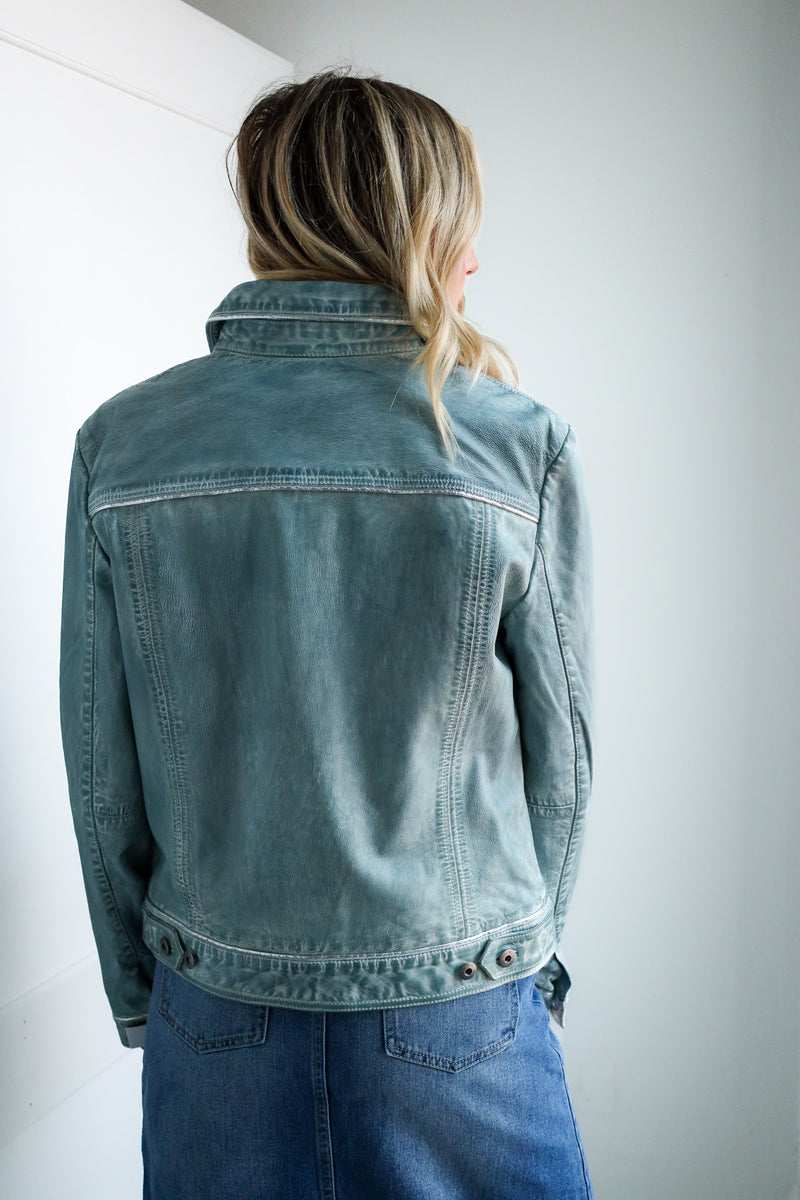 Person wearing a denim jacket and jeans against a plain background