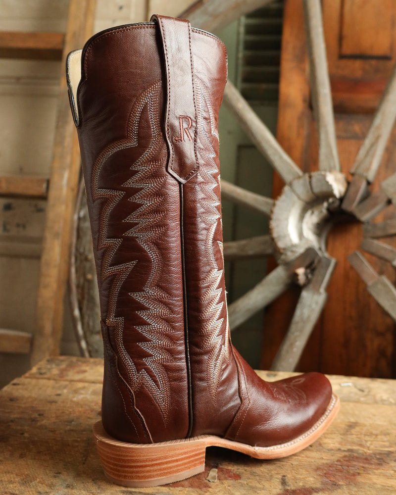 Brown cowboy boot with intricate design on a rustic background