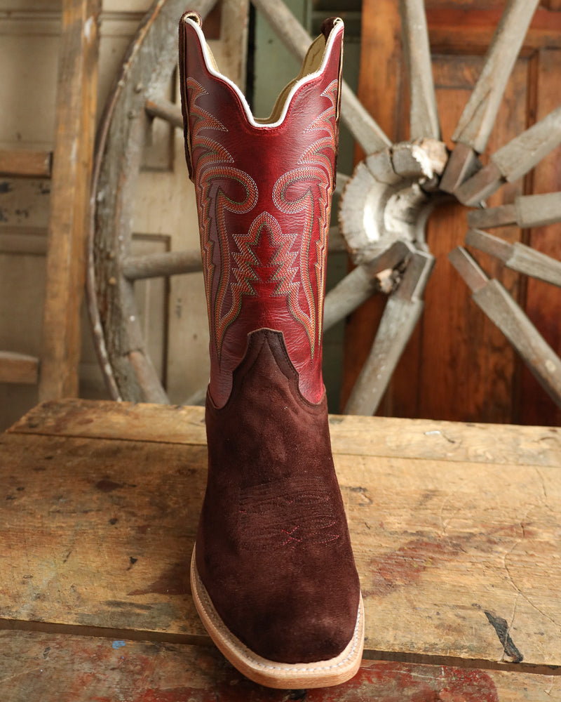 Brown cowboy boot with red interior against a rustic wooden background
