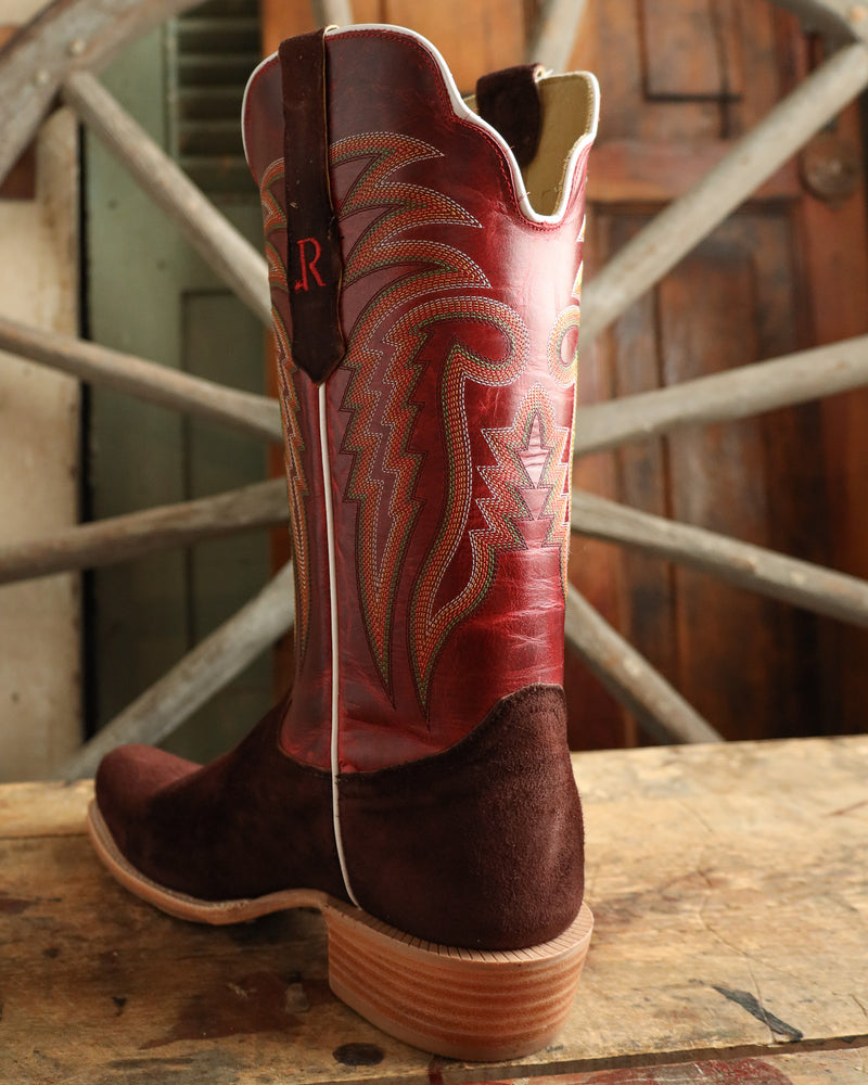 Red and brown cowboy boot with intricate patterns on a wooden surface.