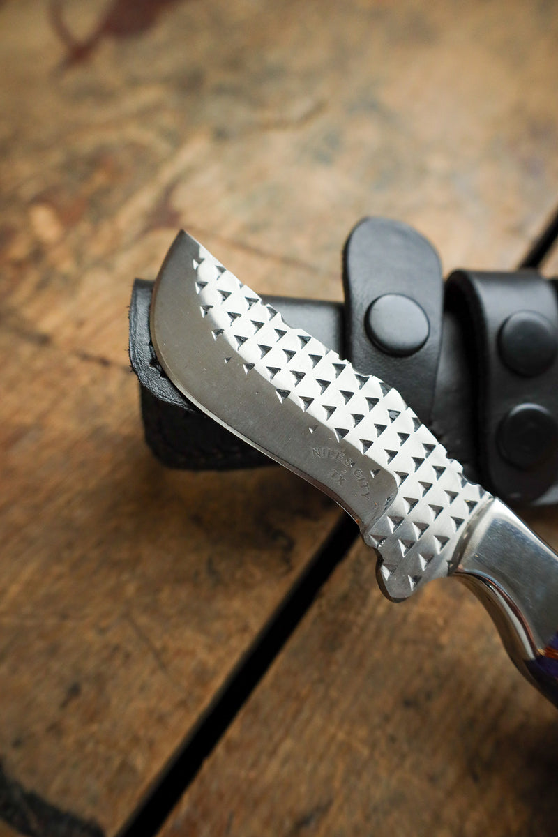 Folding knife with textured blade on a wooden surface