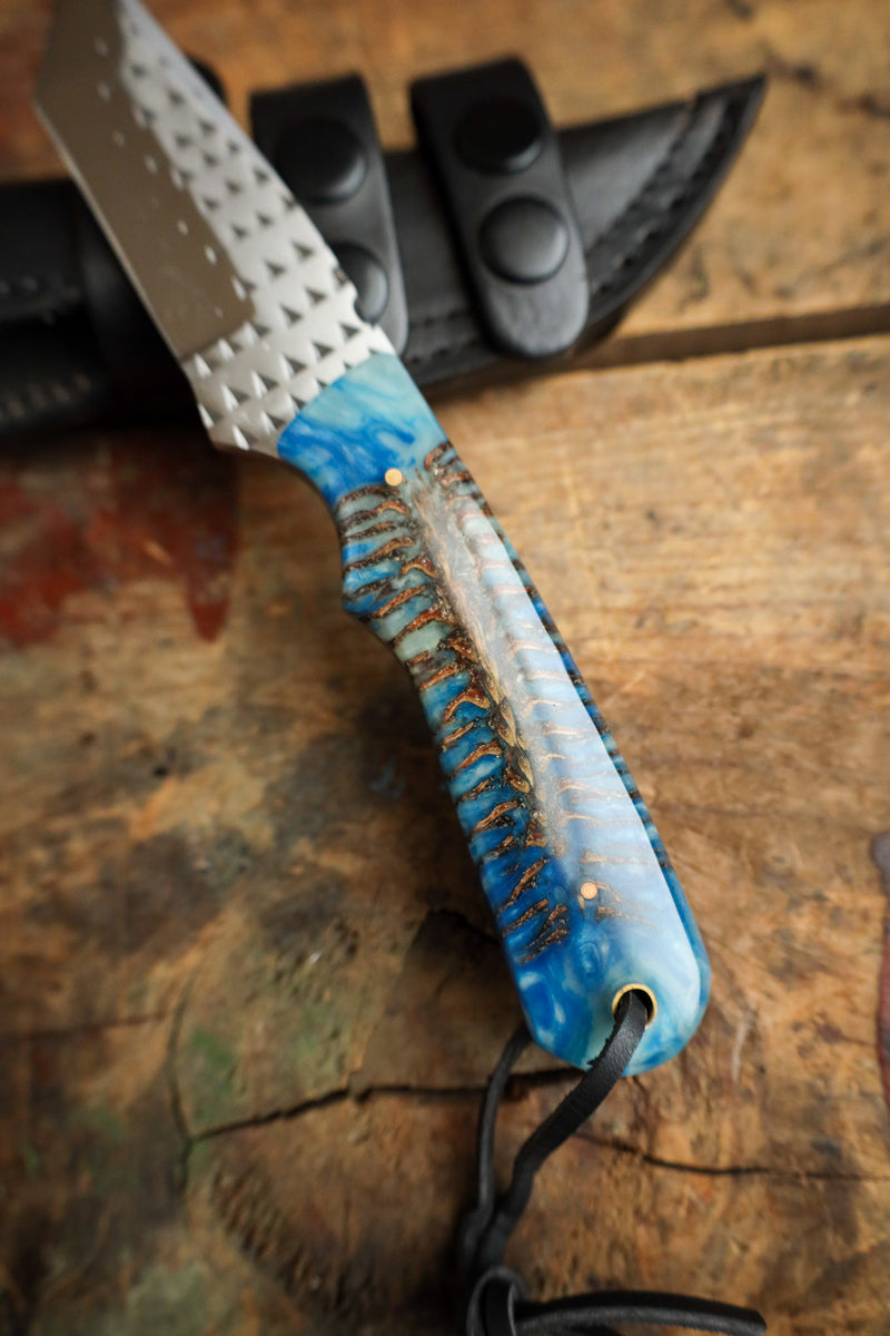 Handcrafted knife with a blue handle on a wooden surface