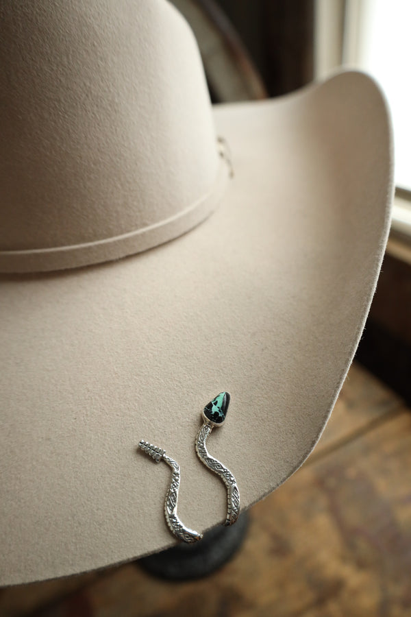 Snake-shaped hat clip with turquoise stone on a beige hat