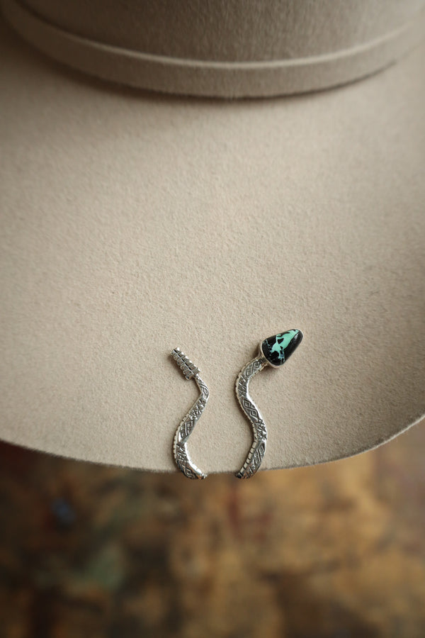 Snake-shaped hat clip with turquoise stone on a beige hat