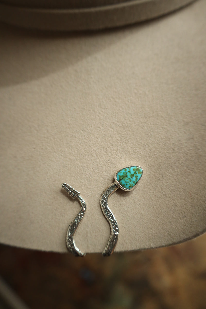 Silver earrings with a turquoise stone on a beige surface
