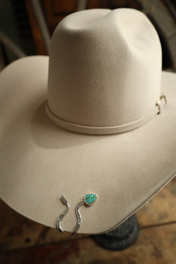 Silver earrings with a turquoise stone on a beige surface